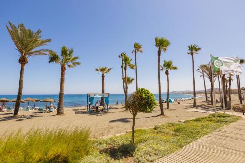 una spiaggia sabbiosa con palme e un parco giochi di Fresh penthouse apartment with great sea views a Casares