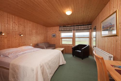 a bedroom with a bed and a desk and a chair at Hotel Raudaskrida in Þóroddsstaður