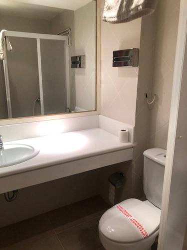 ein Badezimmer mit einem Waschbecken, einem WC und einem Spiegel in der Unterkunft Abeliona Guesthouse in Ambeliona