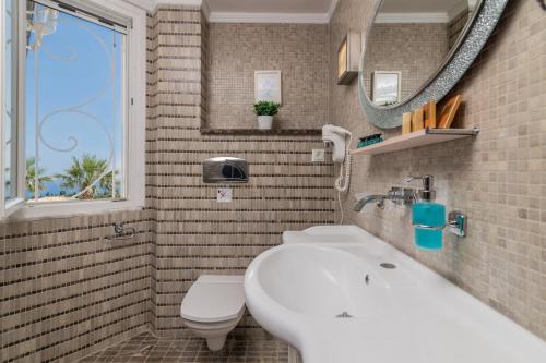 a bathroom with a sink and a toilet and a mirror at Frido Luxury Villa with Jacuzzi in Akrotiri