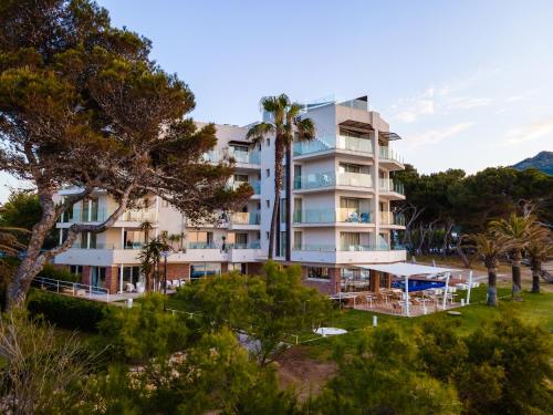 an apartment building with palm trees and a resort at Melbeach Hotel & Spa - Adults Only in Canyamel