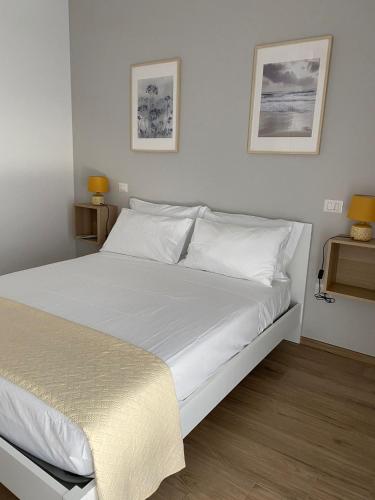 a white bed in a bedroom with two pictures on the wall at Casa simone 2 in Conversano