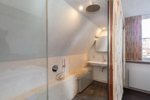 uma casa de banho com um chuveiro, uma banheira e um lavatório. em The Loft 300 - R Q C em Haia