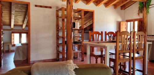 a living room with a table and a dining room with wooden stairs at Donde Elvira in Valderromán