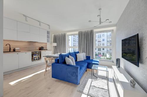 a living room with a blue couch and a kitchen at Downtown Apartments City Center Angielska Grobla in Gdańsk