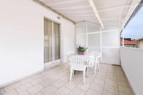 eine weiße Terrasse mit einem Tisch und Stühlen auf dem Balkon in der Unterkunft Residence Barusso in Alassio
