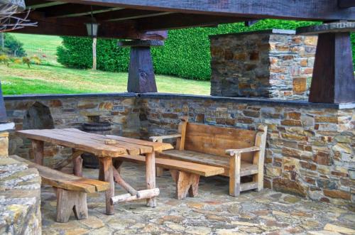 a wooden picnic table and bench under a stone wall at Pajar in Braña