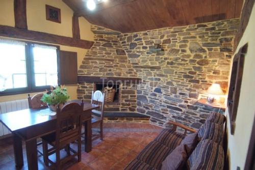 a living room with a stone fireplace and a dining table at Pajar in Braña