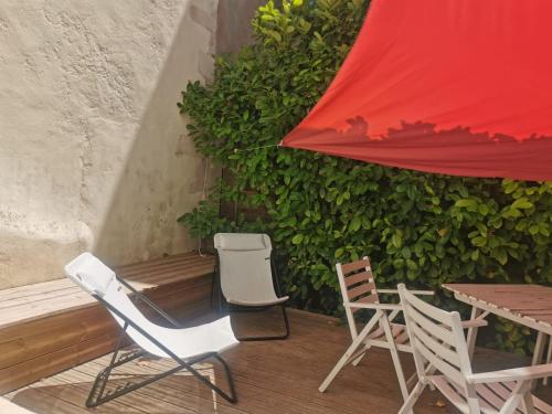 - une terrasse avec 2 chaises, une table et un parasol rouge dans l'établissement La Maison de ville 76m2 avec terrasse de 22m2, à La Rochelle