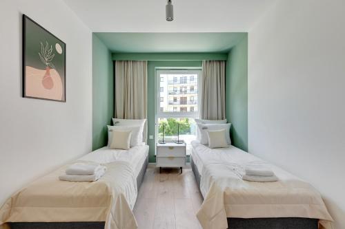 two beds in a room with a window at Downtown Apartments City Center Angielska Grobla in Gdańsk