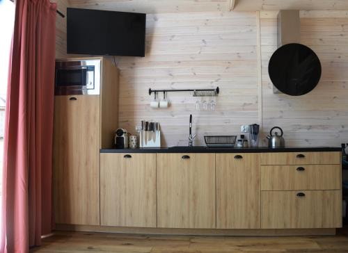 a kitchen with wooden cabinets and a television on the wall at Morska Szyszka & Leśne SPA in Odargowo