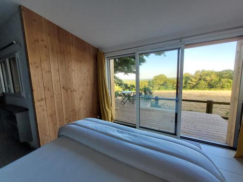 ein Schlafzimmer mit einem Bett und einem großen Fenster in der Unterkunft Le Refuge de la Doucette in Paimpont
