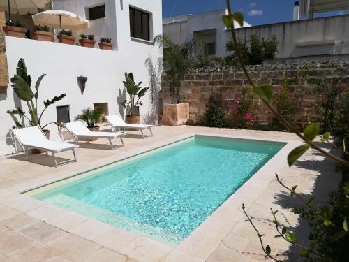 a swimming pool in a yard with chairs and a house at Dimora Maltese in Morciano di Leuca