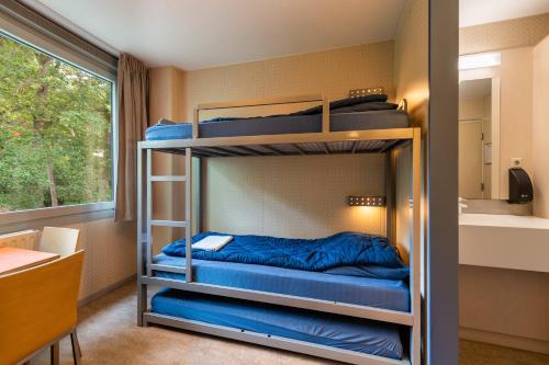 two bunk beds in a room with a window at Stayokay Hostel Soest in Soest