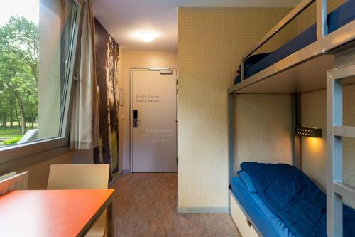 a room with a bunk bed and a table and a door at Stayokay Hostel Soest in Soest