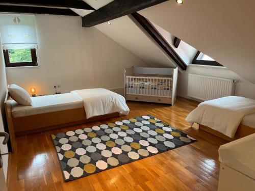 a attic bedroom with two beds and a crib at Riverside Villa Avo - Apartment Sara in Spodnja Idrija