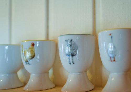 four white cups sitting on top of a table at The Tower, Moray Firth Holiday Home in Kinloss