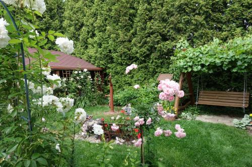 a garden with pink and white flowers and a bench at Apartament Danuta Mrągowo in Mrągowo