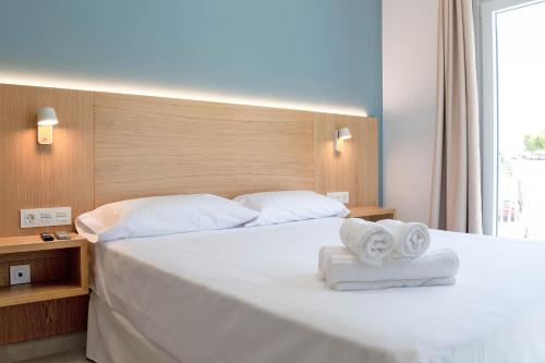 una camera da letto con un grande letto bianco con asciugamani di Rio Salado Conil Hostal a Conil de la Frontera