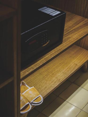 a drawer with a box and a pair of sandals on a shelf at Sima Hotel Kuta Lombok in Kuta Lombok