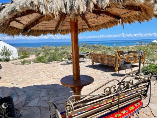 a patio with two benches under a straw umbrella at Ak-Tengir Yurt Resort in Tossor