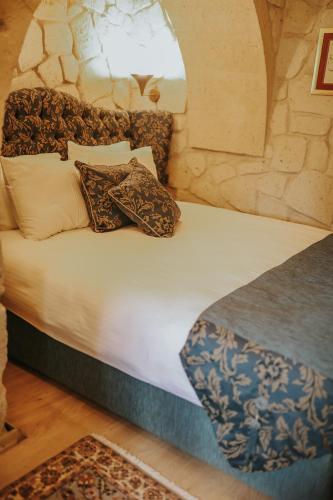 a bed with pillows on it in a room at Elaa Cave Hotel in Ortahisar