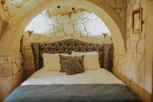 a bedroom with a stone wall with a bed at Elaa Cave Hotel in Ortahisar
