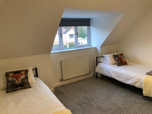 a attic room with two beds and a window at Surrey - Private House with Garden & Parking 13 in Wentworth