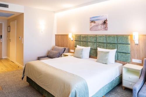 ミエンジズドロイェにあるBel Mare Aqua Resortの大きなベッドと椅子2脚が備わるホテルルームです。