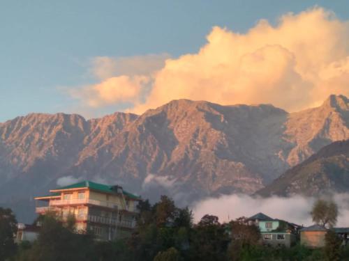 a building in front of a mountain range at Marina Group of Hotels Mount Edge #Free Parking-Mcleodganj 2 km- Bhagsunag 4 km in Dharamshala