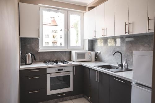 a kitchen with white cabinets and a sink and a microwave at Lubelska in Kołobrzeg