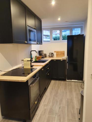 - une cuisine avec des armoires noires et un réfrigérateur noir dans l'établissement Cavalaire Sur Mer, à Cavalaire-sur-Mer