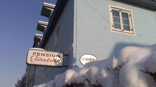 a building with a sign and a pile of snow at Pension Elisabeth - Rooms & Apartments in Salzburg