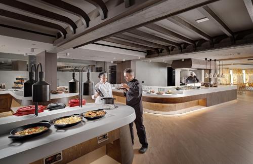 two men standing in a kitchen with food at Nautilux Rethymno by Mage Hotels in Rethymno Town