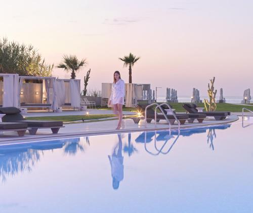 a woman standing on the edge of a swimming pool at Nautilux Rethymno by Mage Hotels in Rethymno Town