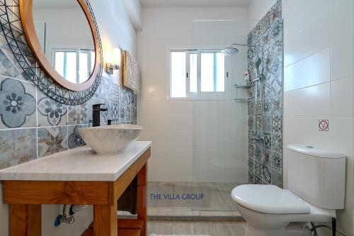 een badkamer met een wastafel, een toilet en een spiegel bij Thea Vista Apartment in Pissouri
