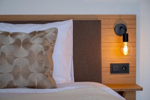 a bed with a pillow and a light on a wall at Hotel Paradis Zandvoort in Zandvoort
