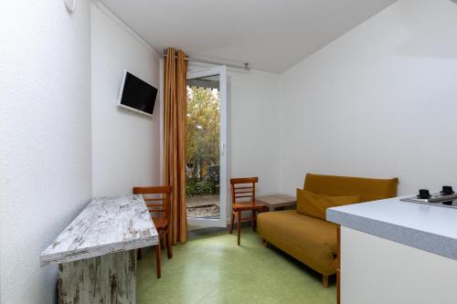 a kitchen and living room with a couch and a table at Village Vacances Le Junka in Vieux-Boucau-les-Bains