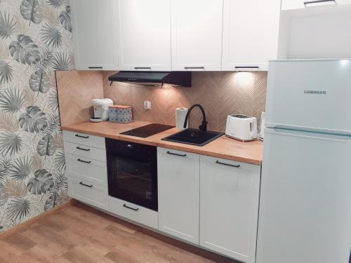 eine Küche mit weißen Schränken und einer Arbeitsplatte in der Unterkunft Apartament Waldi in Kołobrzeg