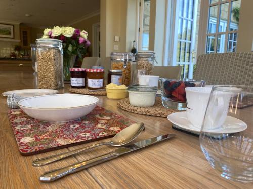 una mesa de madera cubierta con platos, tazones y utensilios en Lower Farm Cottage, en Beaminster