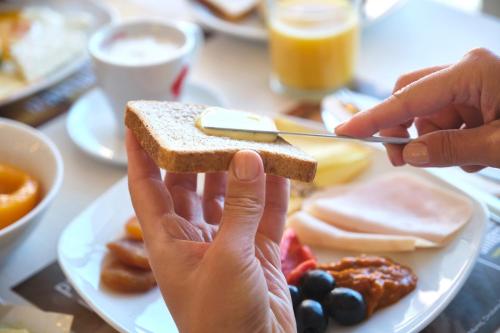 a person holding up a piece of toast on a plate of food at Continental Forum Constanta in Constanţa