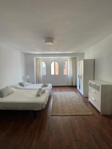 - une grande chambre blanche avec 2 lits et une commode dans l'établissement IRUA APARTAMENTOS, à Ronda