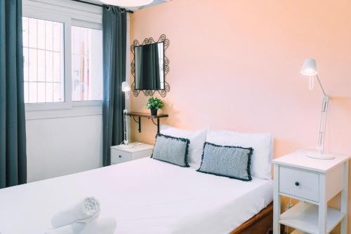 a bedroom with a white bed with blue pillows at Cozy place next to Park Güell in Barcelona