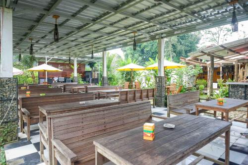 un restaurante al aire libre con mesas de madera y sombrillas en RedDoorz At Jalan Raya Baturaden, en Rempawah