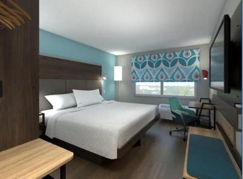 um quarto com uma cama, uma cadeira e uma janela em Tru By Hilton Indianapolis Lawrence, In em Indianápolis