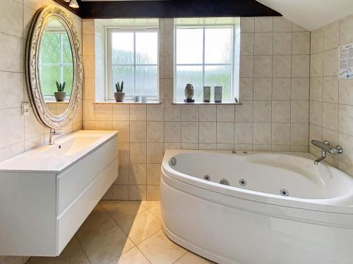 ein großes Bad mit einer großen Badewanne und einem Spiegel in der Unterkunft 8 person holiday home in Toftlund in Vestergård