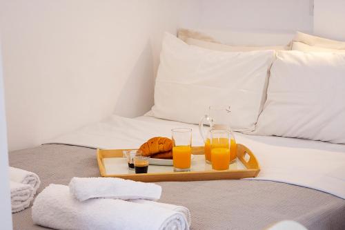 a tray of orange juice and two glasses on a bed at Stylish Modern Studio, Chalkida centre, seaside in Chalkida