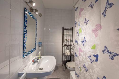 een badkamer met een wastafel en een toilet met vlinders op het douchegordijn bij Ático en Portonovo 200m de la Playa. + WIFI in Portonovo