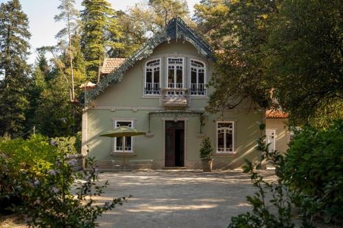 a green house with a large window and trees at The Grove Houses in Guimarães