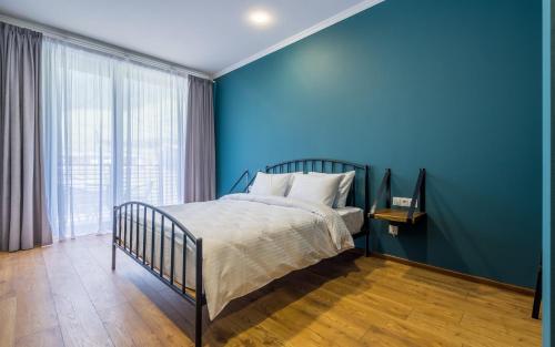 a blue bedroom with a bed and a large window at Hotel Darchi Kazbegi in Stepantsminda